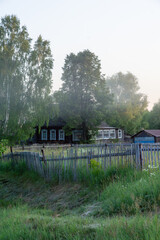 Scenic rural landscape featuring a wooden house surrounded by lush greenery, tall trees, and a...