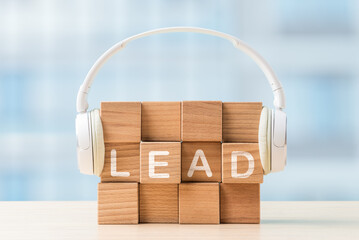 Creative wooden blocks spelling lead with a white headphone on top, symbolizing audio and learning in a modern workspace setting