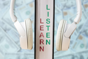 Headphones on a vertical surface with words learn and listen emphasizing the importance of education and audio engagement