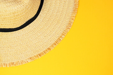 Top view of part of summer beach hat on bright yellow background