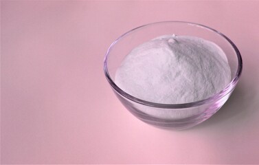 Spa salt in a glass bowl on a pink background with copy space