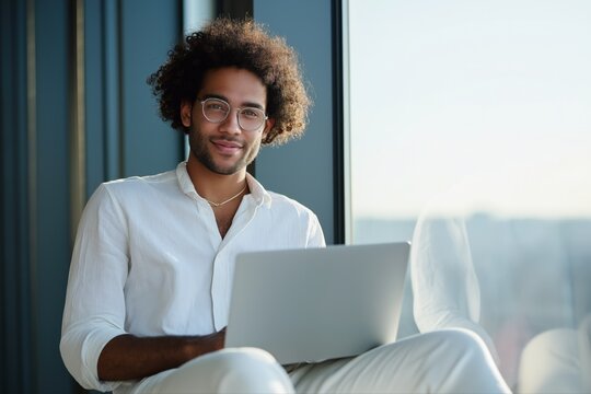 Smiling young african male with laptop in modern office setting