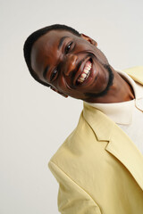 Smiling Man in a Yellow Suit Poses Against a Light Background, Radiating Confidence and Joy During a Studio Session