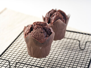 Baked Chocolate Muffins on a black wire cooling rack side view of baked dessert