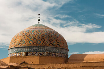 Majestic Persian dome adorned with Quranic inscriptions and geometric tilework under a vibrant sky in Yazd, Iran — a masterpiece of Islamic architecture and heritage.