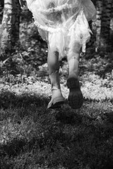 A woman wearing a lace dress and boots is running through a forest