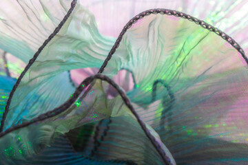 Abstract close-up of shimmering iridescent fabric with flowing pastel waves and delicate textures,...