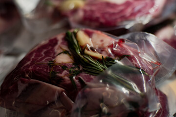 Vacuum sealed raw beef steaks with fresh rosemary garlic and herbs prepared for sous vide cooking...