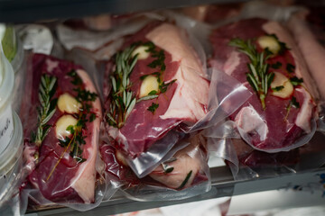 Vacuum sealed raw beef steaks with garlic rosemary and parsley arranged for sous vide cooking or...
