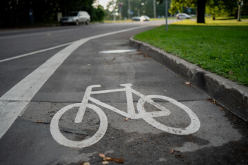 Fototapeta premium Bicycle lane symbol painted on urban asphalt road with white marking showing dedicated cycling path for eco friendly transportation safety and sustainable city mobility