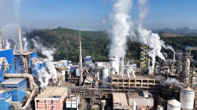Vis&atilde;o a&eacute;rea ind&uacute;stria de papel e celulose com chamin&eacute;s e caldeiras soltando fuma&ccedil;a, evidenciando polui&ccedil;&atilde;o do ar e impactos ambientais gerados pelos processos industriais modernos.