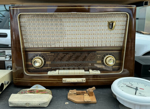 Villach, Austria - May 12, 2024: Vintage radio with wooden finish and retro design displayed at flea market, surrounded by various antique items and collectibles