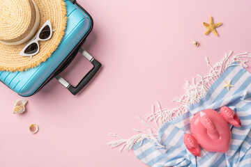 Flat lay of travel essentials including a suitcase, straw hat, towel, and beach accessories on a...