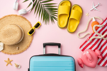 Flat lay of vacation accessories including a suitcase, hat, sunglasses, and flip-flops
