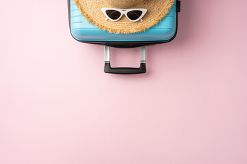 Top view of a blue suitcase paired with a summer hat and stylish sunglasses, set against a pastel...