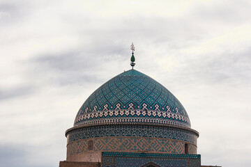 Majestic Persian dome adorned with Quranic inscriptions and geometric tilework under a vibrant sky in Yazd, Iran — a masterpiece of Islamic architecture and heritage