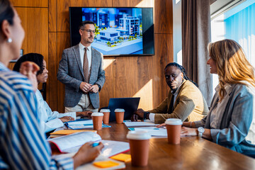 Diverse group of business people working in a meeting room discussing building design and plans.