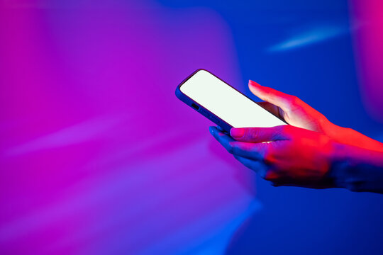Hand using smartphone under neon lights