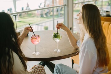 Two young women enjoying refreshing drinks at a cafe