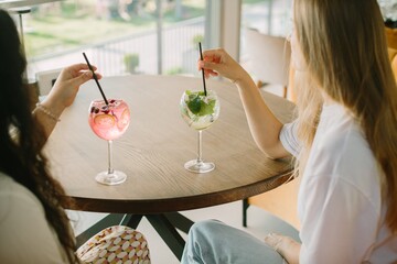 Two young women enjoying refreshing drinks at a cafe