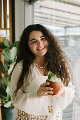 Young woman smiling and holding a tropical drink in a cafe