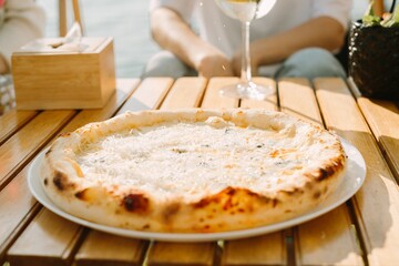 Delicious four cheese pizza on a wooden table in outdoor cafe