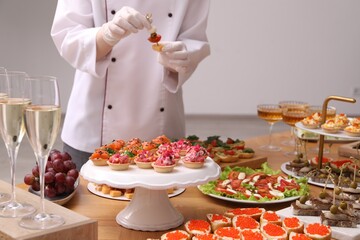 Chef arranging appetizers on buffet table, selective focus