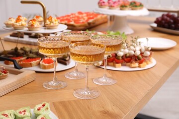 Buffet menu. Glasses of sparkling wine and tasty appetizers on table, closeup