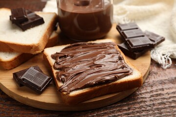 Bread with chocolate butter and pieces on wooden table, closeup
