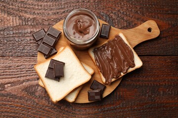 Tasty chocolate butter, pieces and bread on wooden table, top view