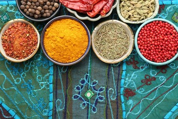 Many different aromatic spices in bowls on table with cloth, flat lay. Space for text