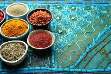 Different aromatic spices on blue tablecloth, closeup. Space for text