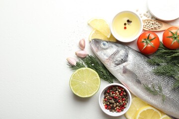Fresh raw seabass fish with spices on white table, flat lay and space for text. Seafood delicacies