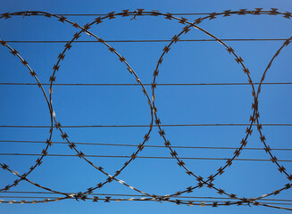 Flat security barrier made of reinforced barbed tape on the fence.