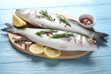 Fresh raw seabass with spices on blue wooden table, closeup. Fish and seafood delicacies