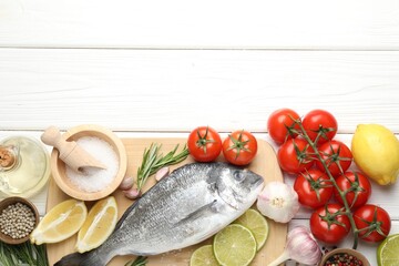 Fresh raw dourade fish with spices on white wooden table, flat lay and space for text. Seafood...