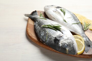 Organic seafood. Fresh raw dorado fish, lemon slices and rosemary on white wooden table, closeup. Space for text