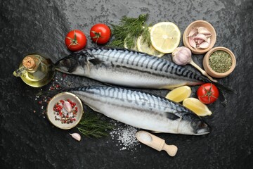 Fresh raw mackerels and spices on black table, flat lay. Seafood delicacies
