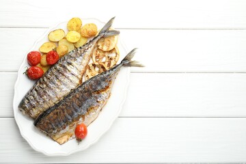 Homemade seafood dish. Tasty roasted mackerels with lemon, tomatoes and potatoes on white wooden table, top view. Space for text