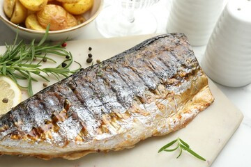 Tasty roasted mackerel with spices and potatoes on white table, closeup. Homemade seafood dish