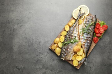 Homemade seafood dish. Tasty roasted mackerels with spices and vegetables on grey table, top view....