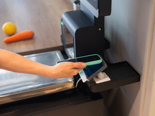 A woman pays using her smartphone at a self-checkout. 