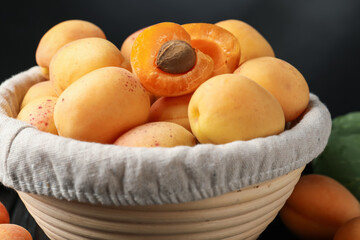 Fresh apricots in basket against black background, closeup