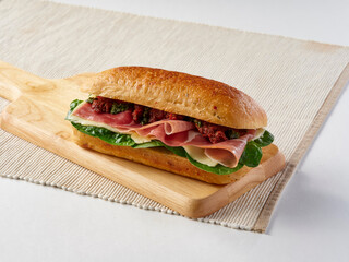 Parma Ham and Mozzarella cheese Sundried Focaccia Sandwich with Tomato and Pesto on a wooden board...