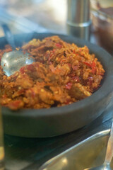 Close-up of sambal tempeh, a traditional Indonesian chili relish made from fermented soybeans, served in a black stone mortar, ready to eat.