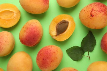 Fresh ripe apricots and leaves on green background, flat lay