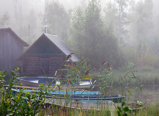 Rowboats on the shore of body of water in the morning fog.