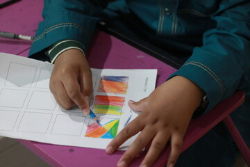Close Up Little Kid Coloring Geometric Shapes on a Paper Sheet Activity
