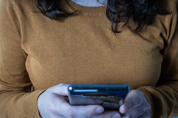 Woman holding smartphone and scrolling screen closely.Female using phone with focused posture,...