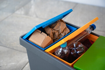 Recycling bin with colorful lids for sorting plastic, paper, and organic waste, placed on a tiled...